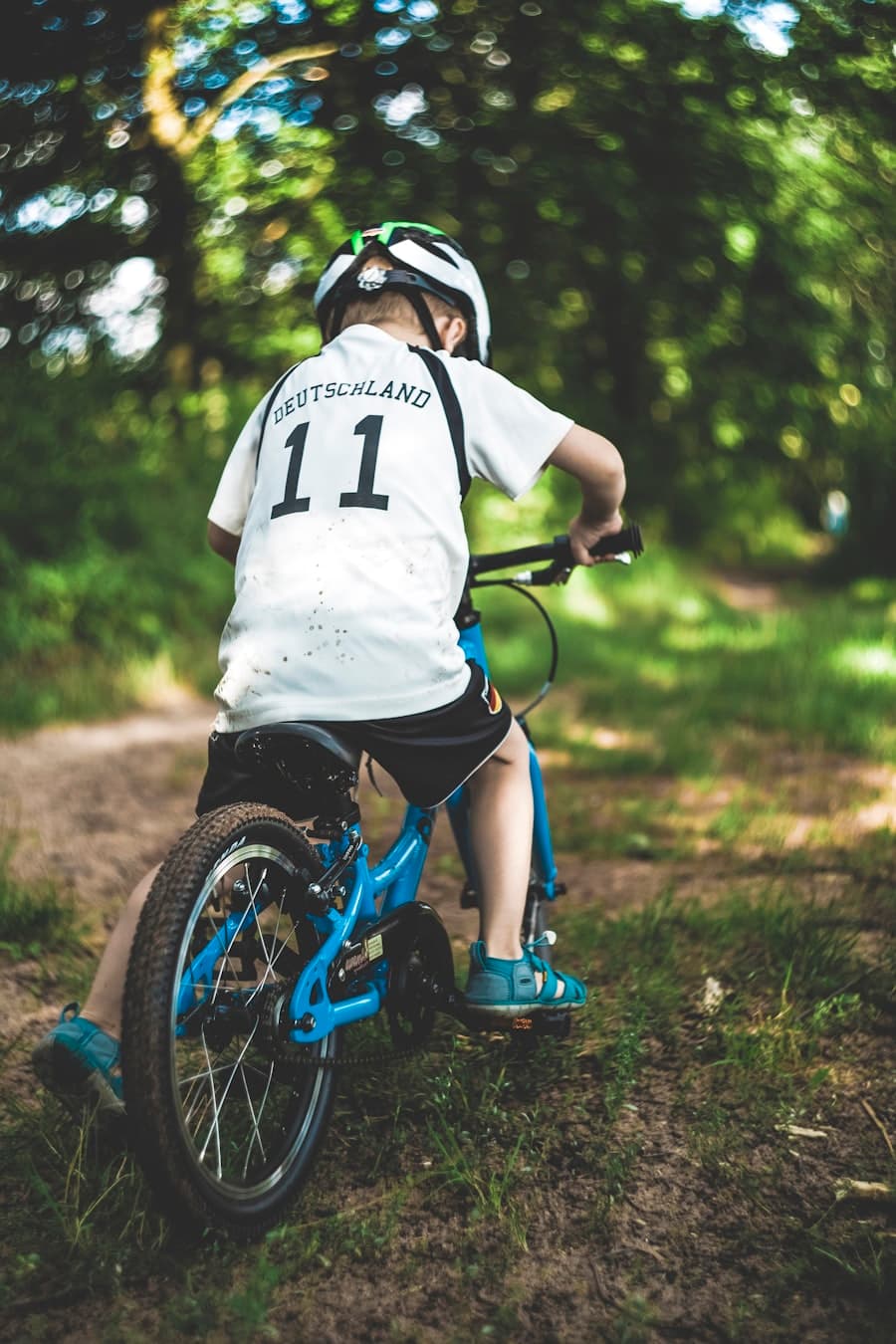 Boy riding a blue kids bicycle through a park