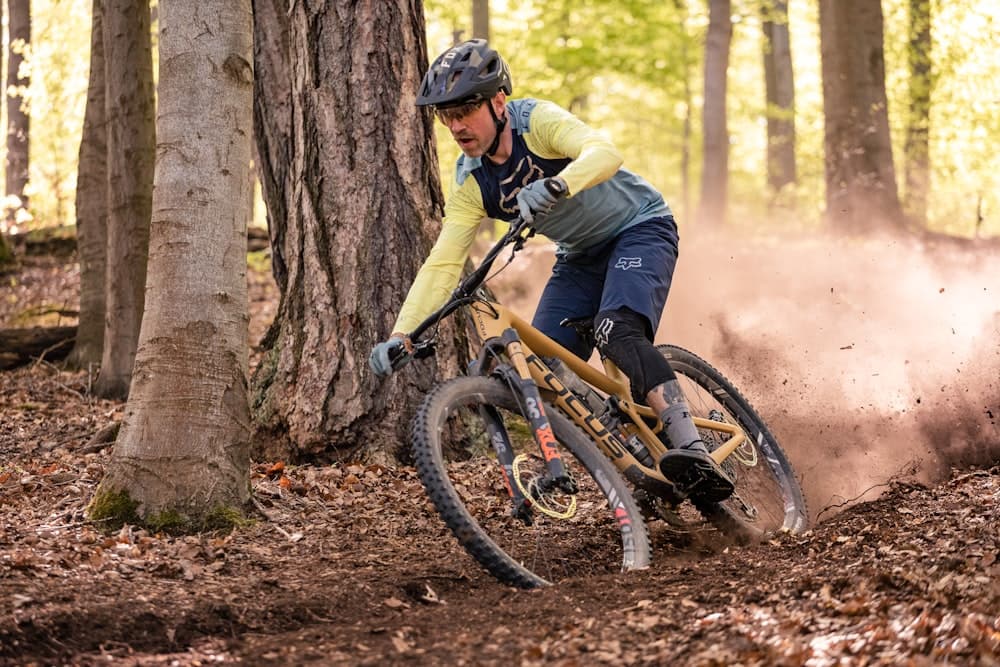 Rider on a mountain bike carving through a forest trail