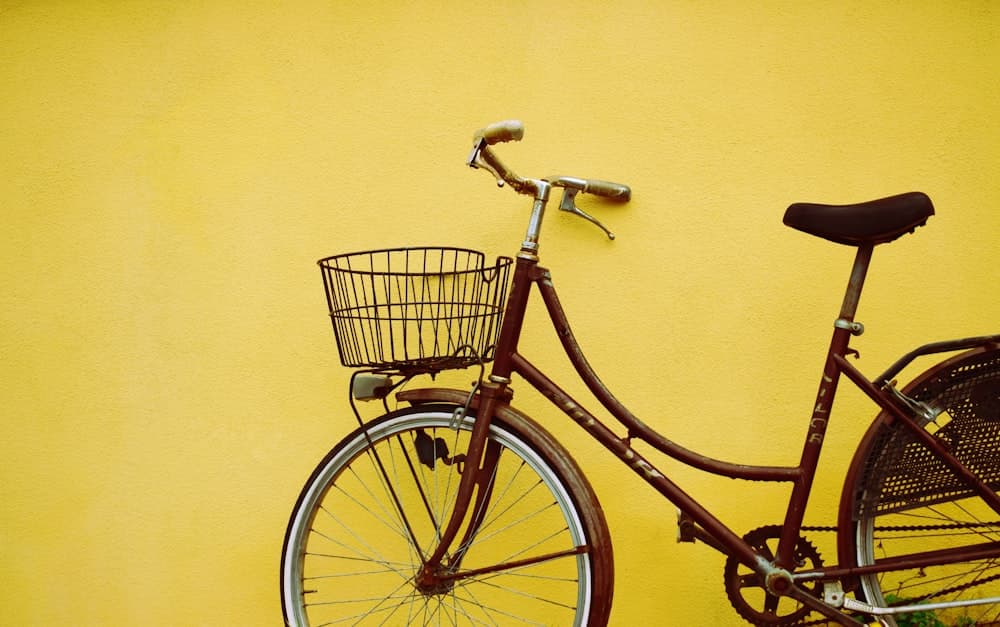 Classic ladies cycle with a basket against a yellow wall