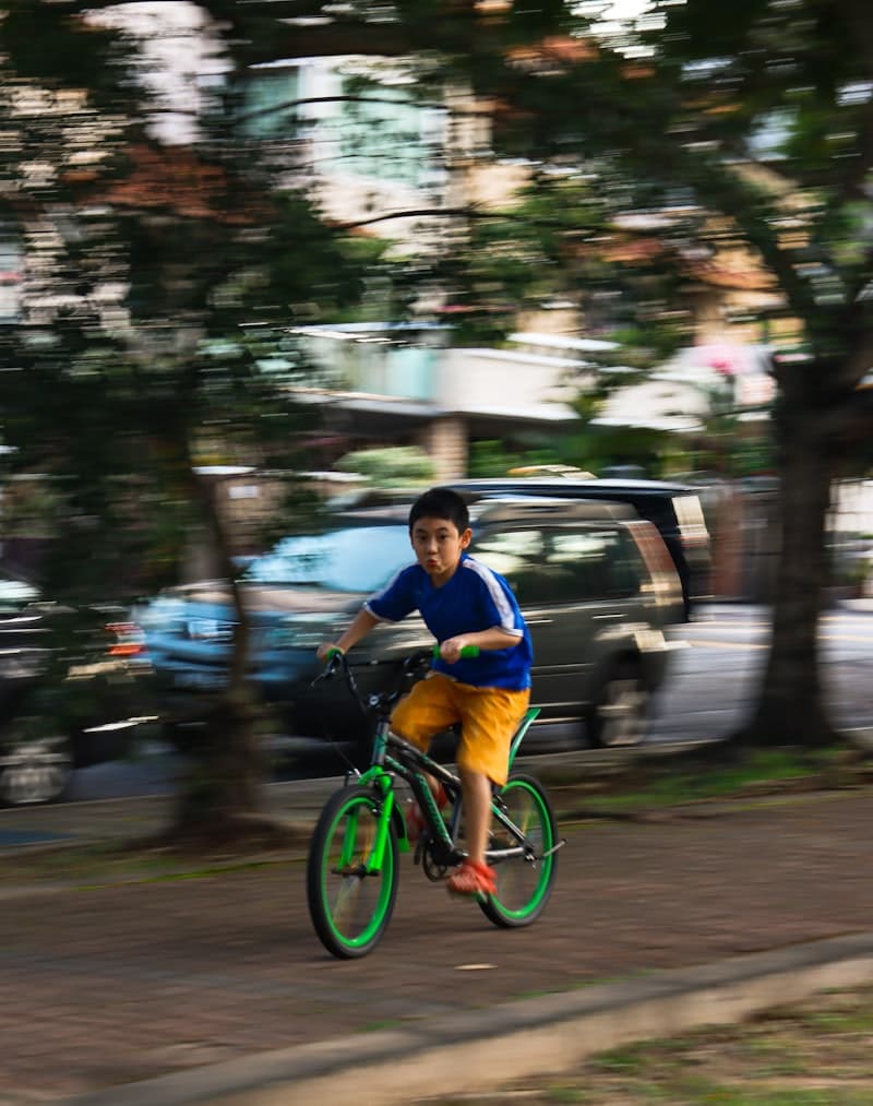 Kid riding a green bicycle at speed